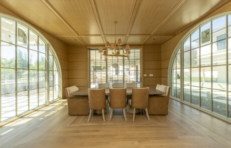Wood ceiling paneling accents a dining room filled with spacious windows and custom wall paneling.