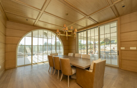 Wood ceiling paneling accents a dining room filled with spacious windows and custom wall paneling.