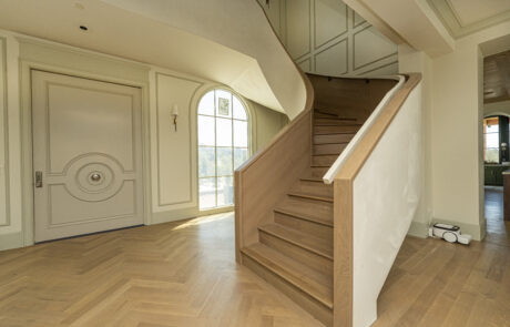 An elegant, modern curving staircase with custom wall paneling in a beautiful home remodel.